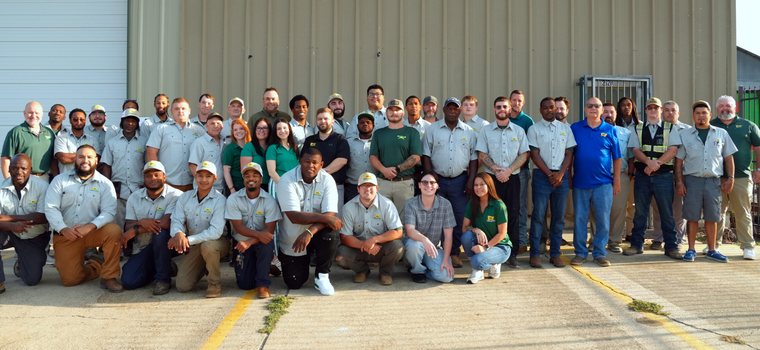 Group photo of diverse team members in uniform posing outdoors in front of a building.