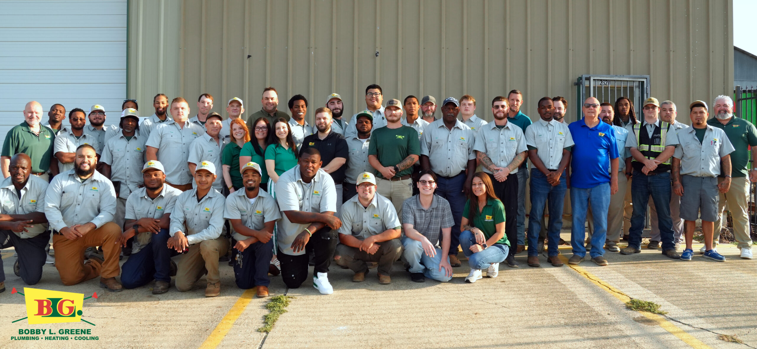 Group photo of Bobby L. Greene team in uniforms outside their facility, specializing in plumbing, heating, cooling.