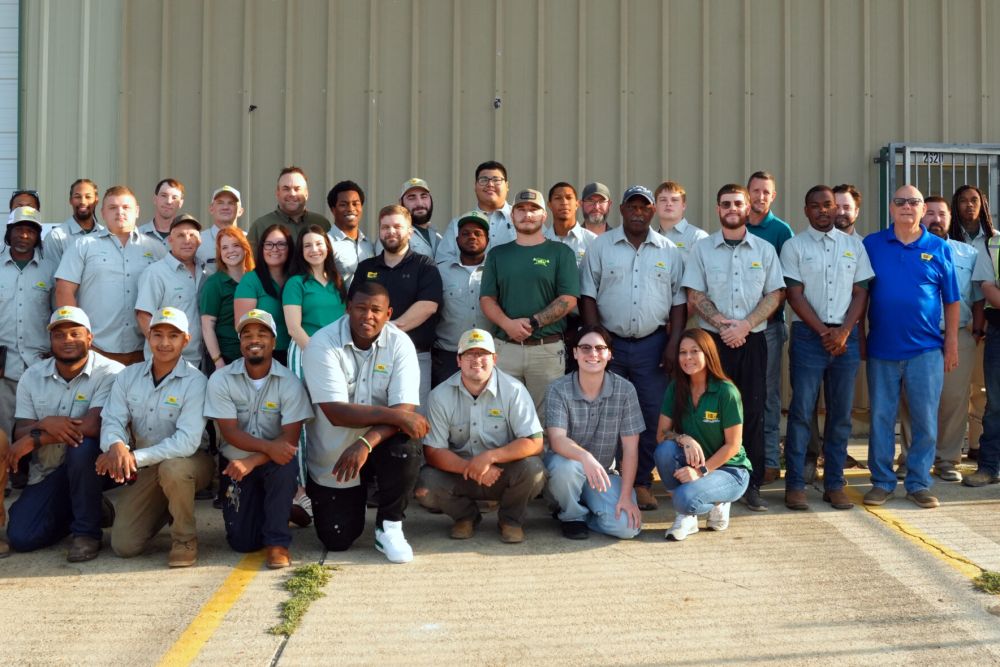 Group photo of diverse team members in uniform posing outdoors in front of a building.