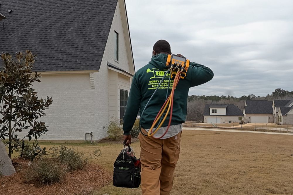 Technician carrying tools and equipment towards house, ready for plumbing or HVAC repair in a suburban neighborhood.