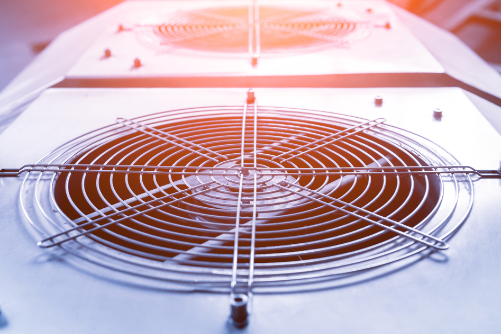 Close-up of industrial cooling fan with metal grille, illuminated by sunlight, illustrating HVAC technology.