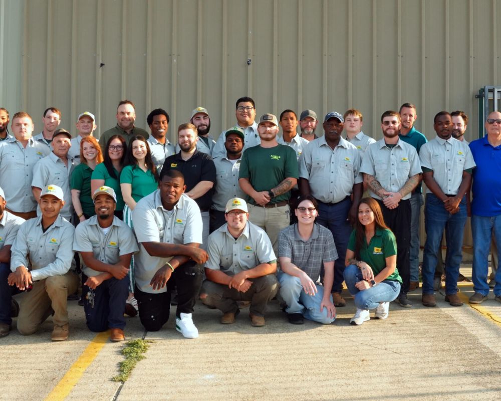 Group photo of diverse team members in uniform posing outdoors in front of a building.